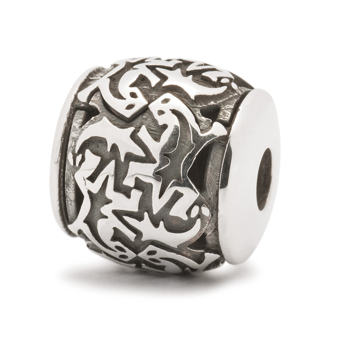 A silver bead with a pattern of black silhouettes of lizards.